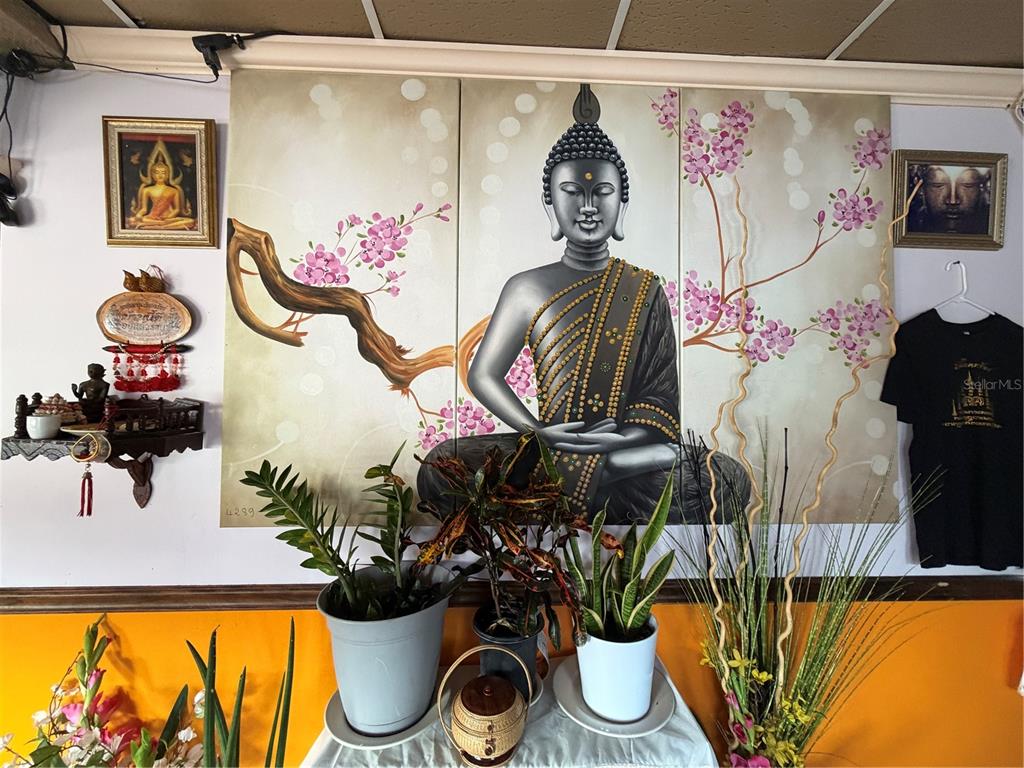 A wall features a large three-panel Buddha painting, smaller framed art, and various potted plants — 5306 SEMINOLE BOULEVARD, ST PETERSBURG, FL