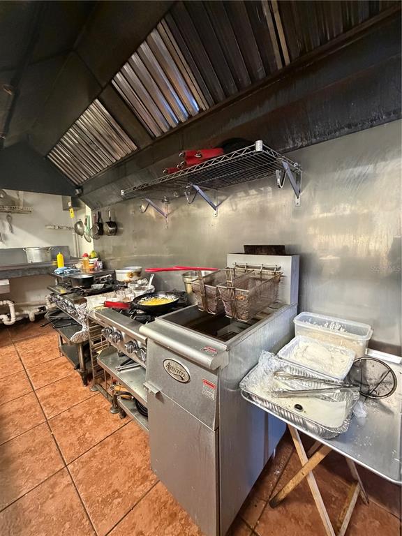 A commercial kitchen features a deep fryer, a gas range, and stainless steel wall panels — 5306 SEMINOLE BOULEVARD, ST PETERSBURG, FL