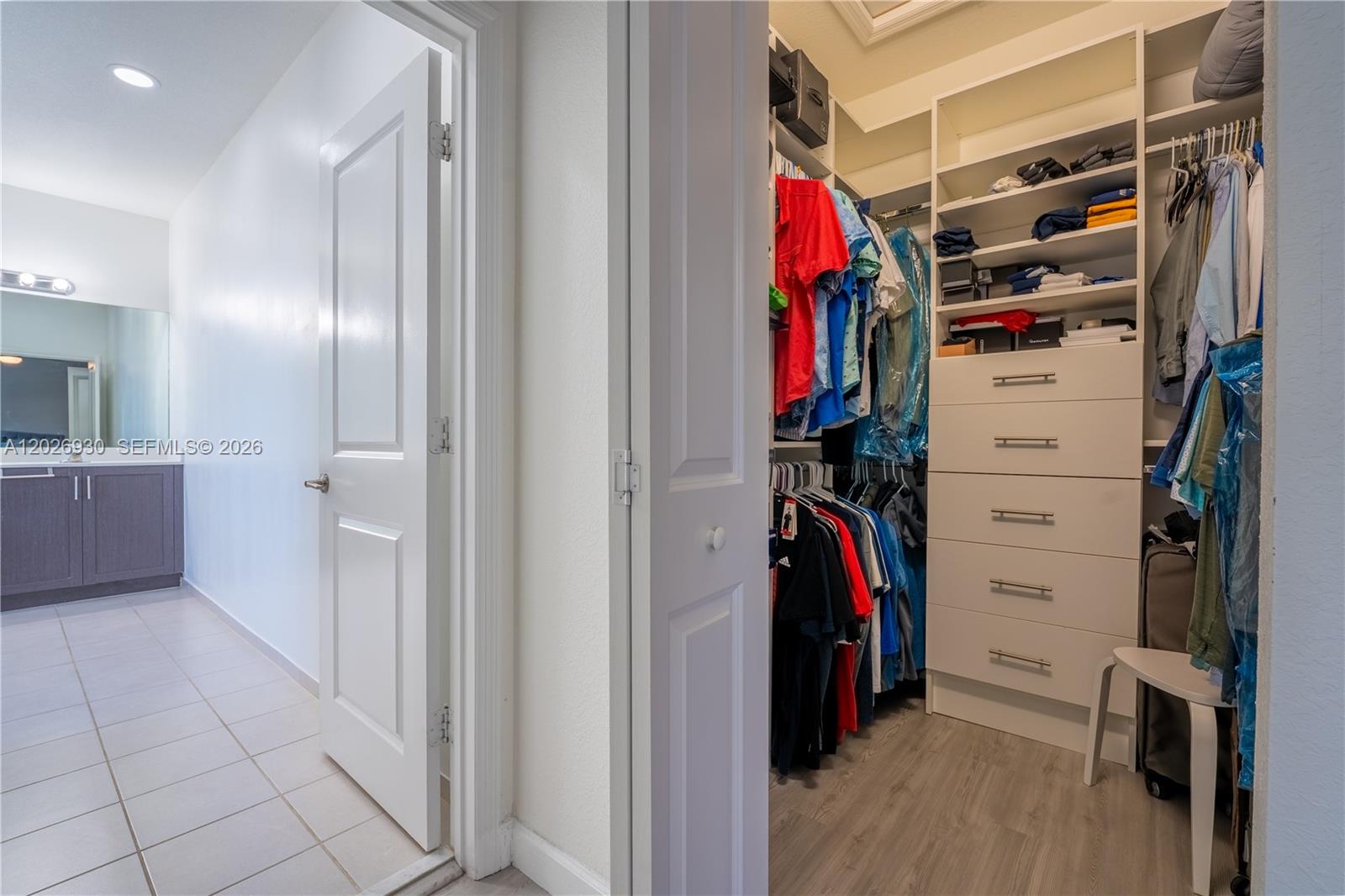 A walk-in closet with built-in shelving and drawers sits adjacent to a tiled bathroom — 2588 SE 2nd St, Homestead FL 33033, HOMESTEAD, FL