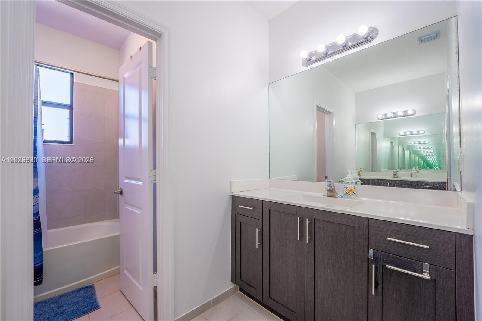 A bathroom features a dark wood vanity with a white countertop and a shower-tub combo — 2588 SE 2nd St, Homestead FL 33033, HOMESTEAD, FL