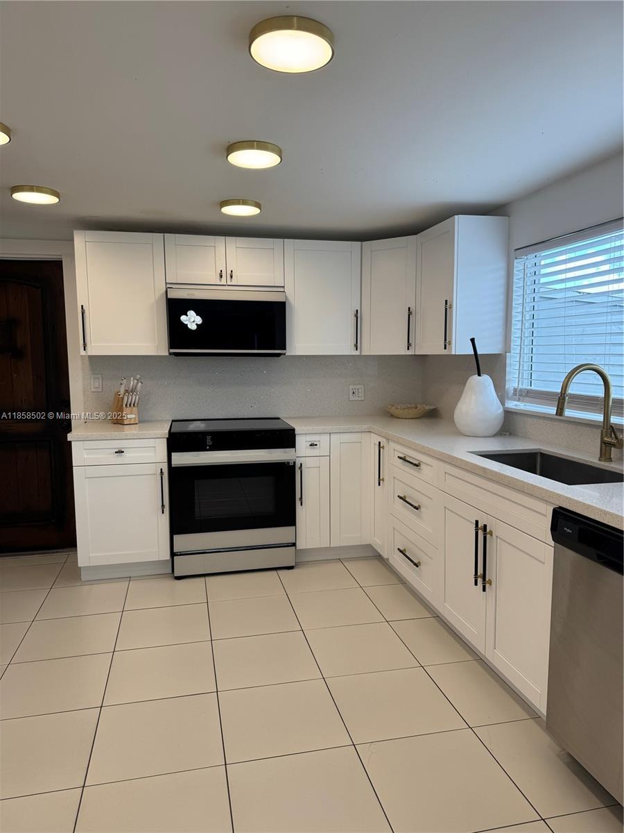 A kitchen features white cabinetry, stainless steel appliances, light countertops, and tile flooring — 1301 Grouper Dr # A, Marathon FL 33050, MARATHON, FL