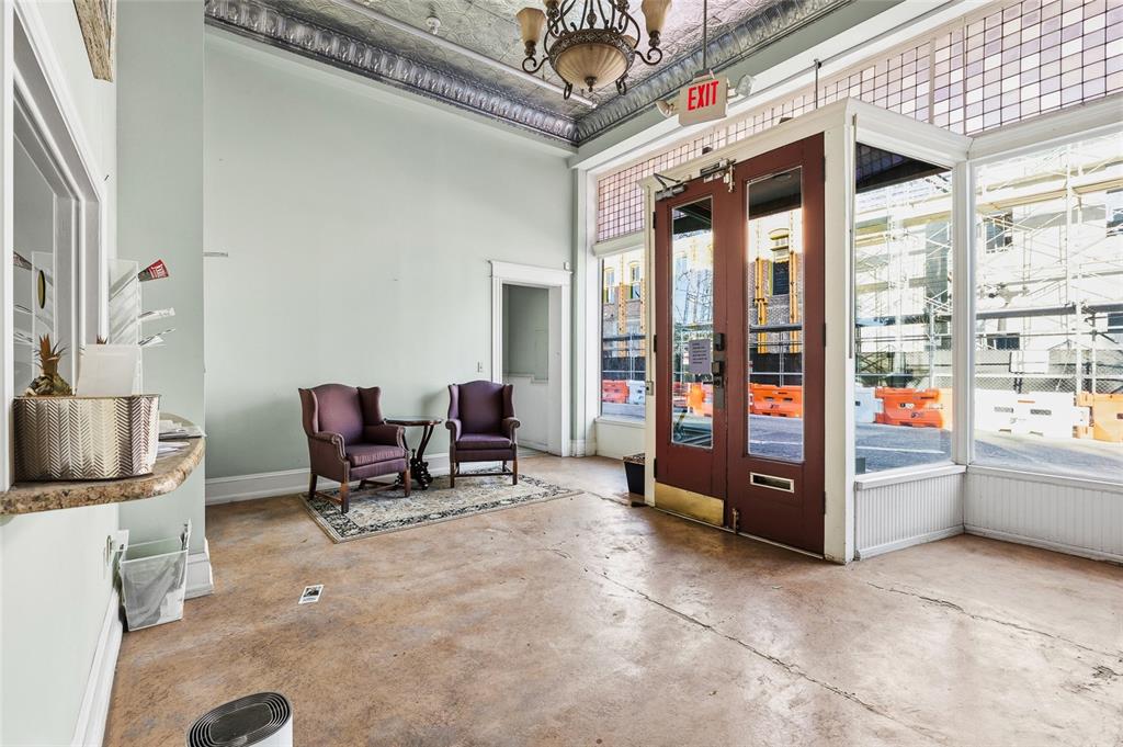 A commercial lobby features a high tin ceiling, two purple chairs, and a glass storefront — 1829 E 7TH AVENUE, TAMPA, FL