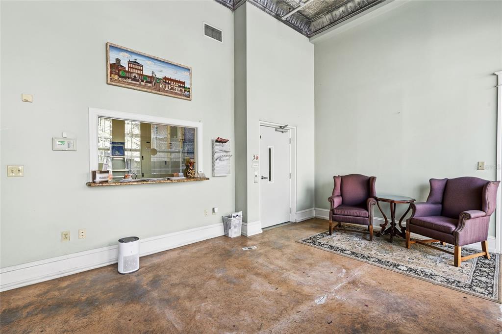 A waiting area with high ceilings, a service window, and two purple armchairs on a rug — 1829 E 7TH AVENUE, TAMPA, FL