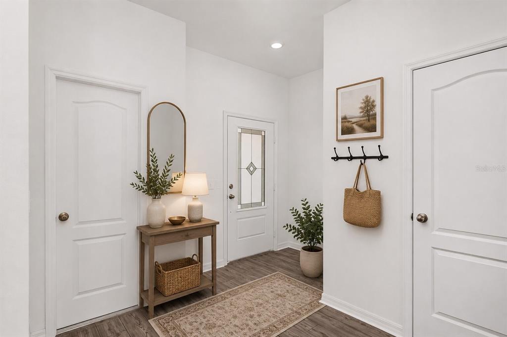 A bright entryway features a wooden console table, a mirror, and a patterned area rug — 572 BAY LEAF DRIVE, POINCIANA, FL