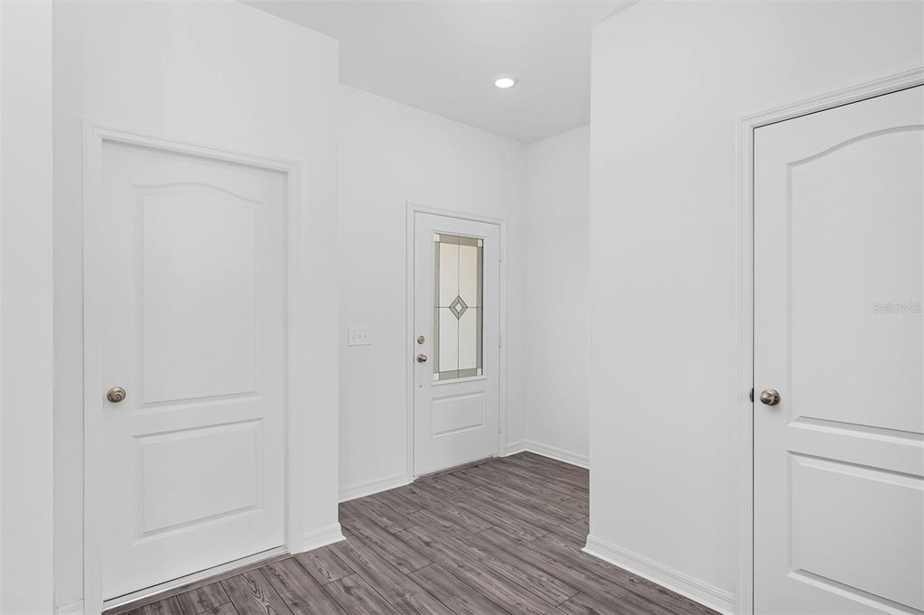 An entryway features white walls, wood-look flooring, and three white interior doors — 572 BAY LEAF DRIVE, POINCIANA, FL
