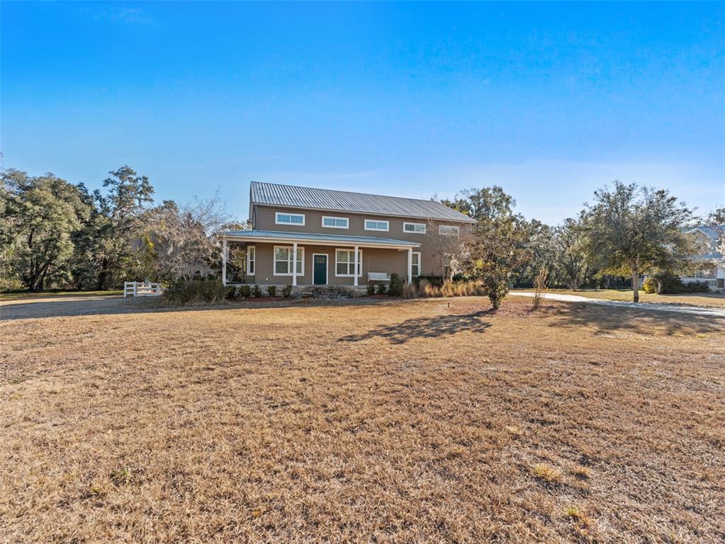 A two-story house with a metal roof and a front porch sits on a lawn — 4702 CYPRESS SERENITY DRIVE, PLANT CITY, FL