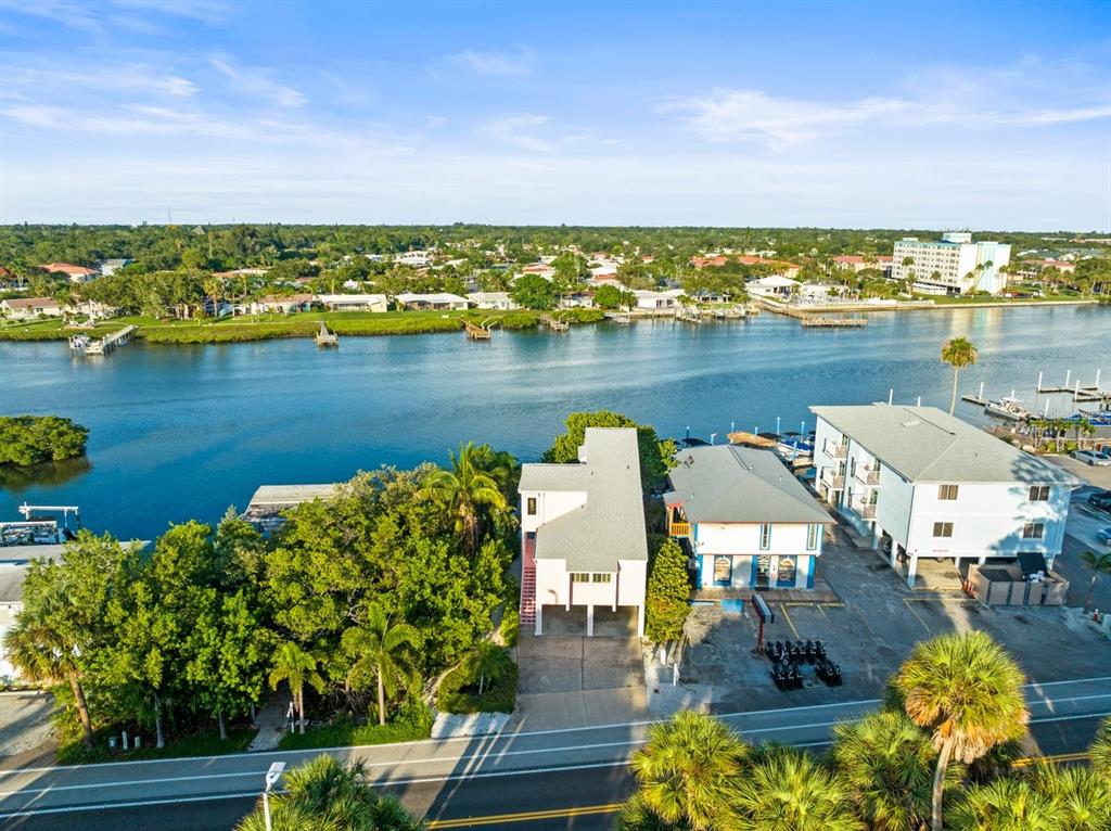 An aerial view shows a waterfront property with a house, a commercial building, and parking — 20051 GULF BOULEVARD, INDIAN SHORES, FL
