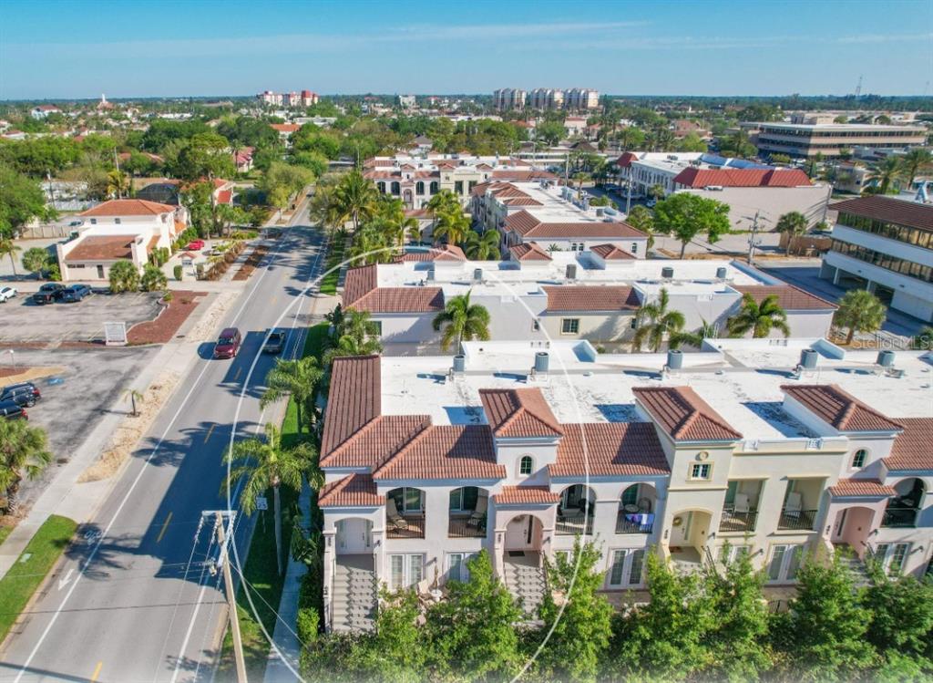An aerial view of a multi-story residential complex with tile roofs next to a road — 455 NOKOMIS AVENUE S UNIT 455, VENICE, FL
