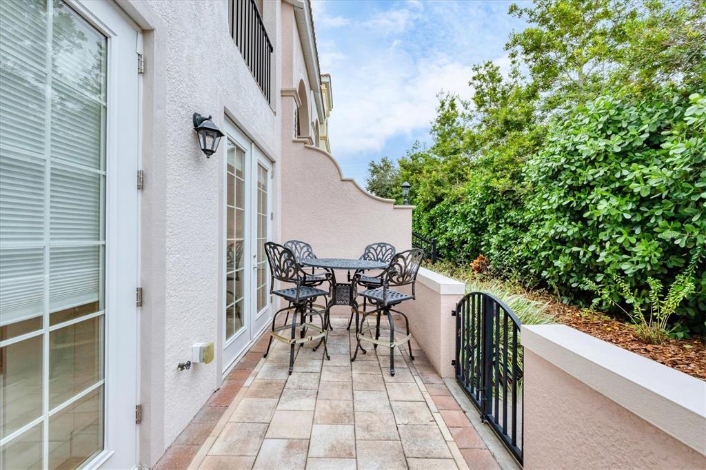 A small outdoor patio features a metal table and four chairs against a stucco wall — 455 NOKOMIS AVENUE S UNIT 455, VENICE, FL