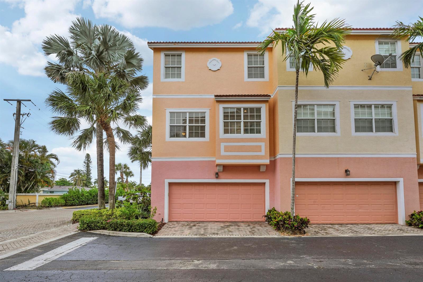 A three-story townhouse with a pink garage, peach siding, and palm trees in front — 115 Harbors Way, Boynton Beach FL 33435, BOYNTON BEACH, FL