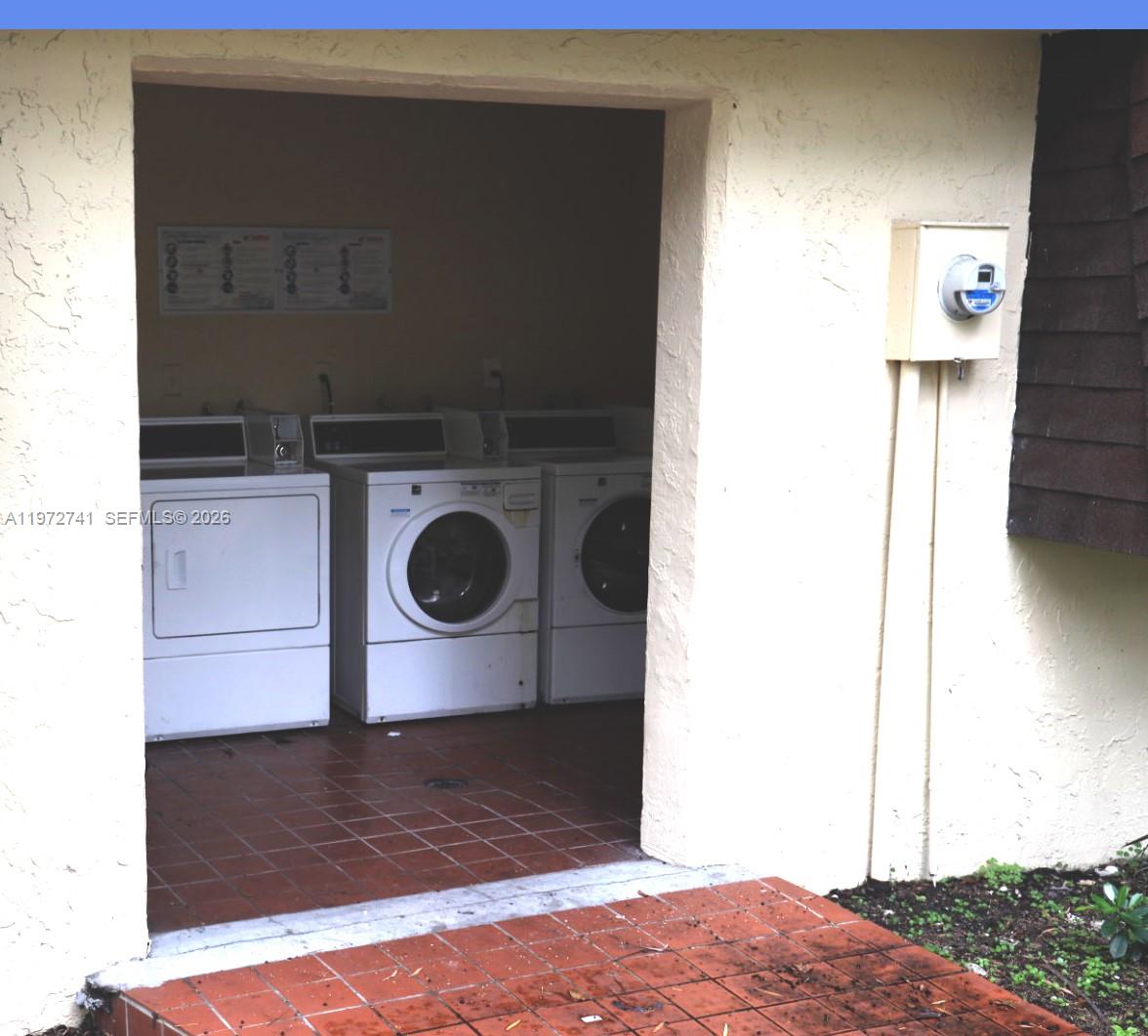 An outdoor laundry area features three white washing machines on a tiled floor — 13714 SW 90th Ave # 25, Miami FL 33176, MIAMI, FL
