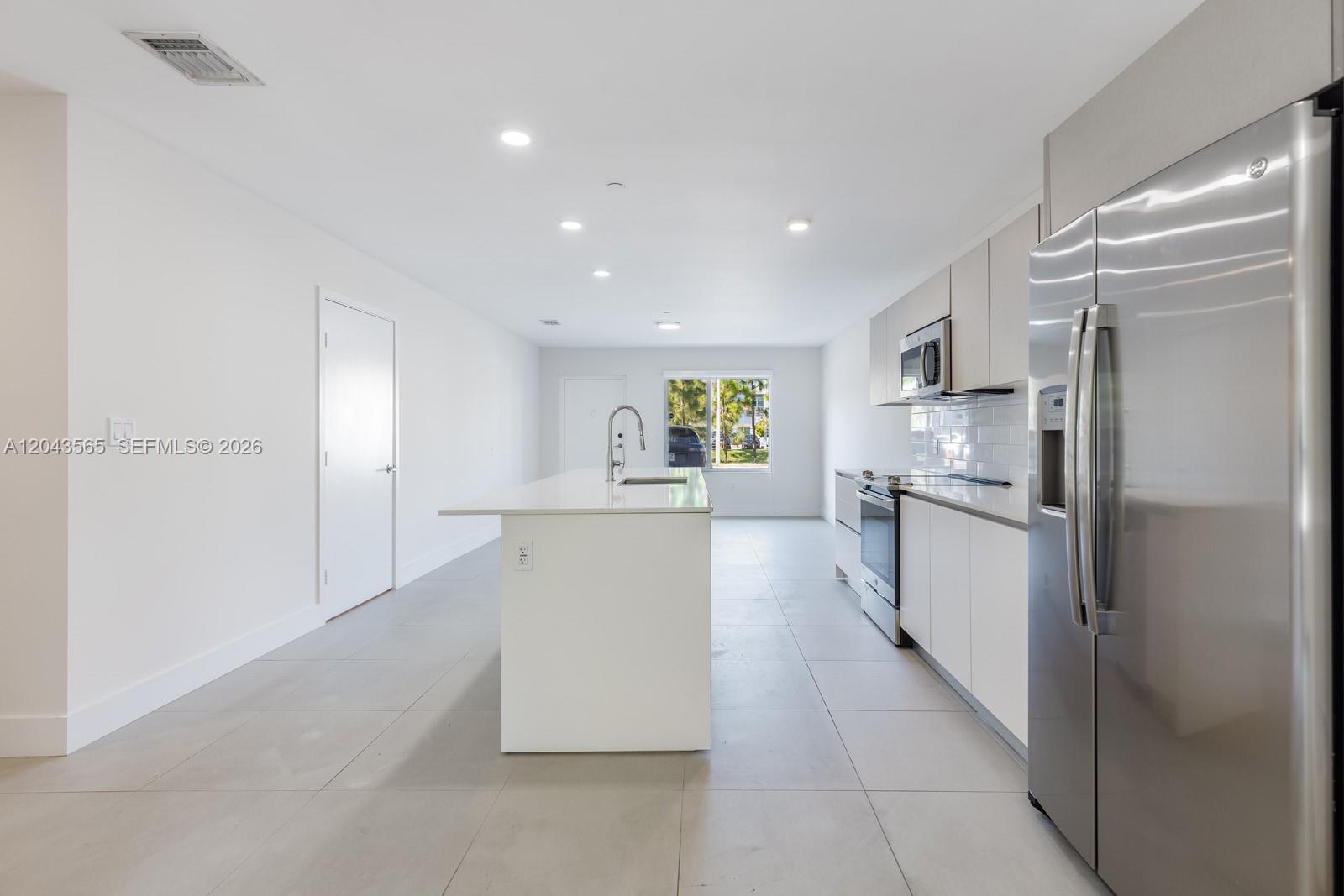 A modern kitchen features white cabinetry, stainless steel appliances, a central island, and tile flooring — 2505 NE 193rd St # 4108, Miami FL 33180, MIAMI, FL