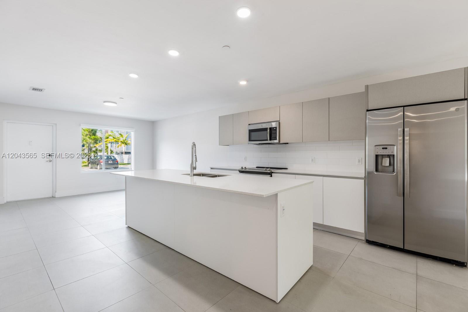 A modern kitchen features white cabinetry, a large center island, and stainless steel appliances — 2505 NE 193rd St # 4108, Miami FL 33180, MIAMI, FL