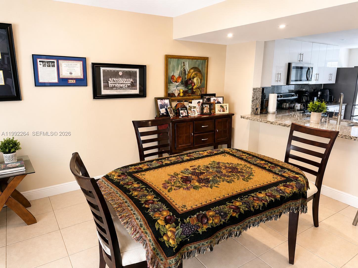 A dining area features a table with a fruit-patterned tablecloth, wooden chairs, and a sideboard — 10060 NW 41st St # 5, Doral FL 33178, DORAL, FL