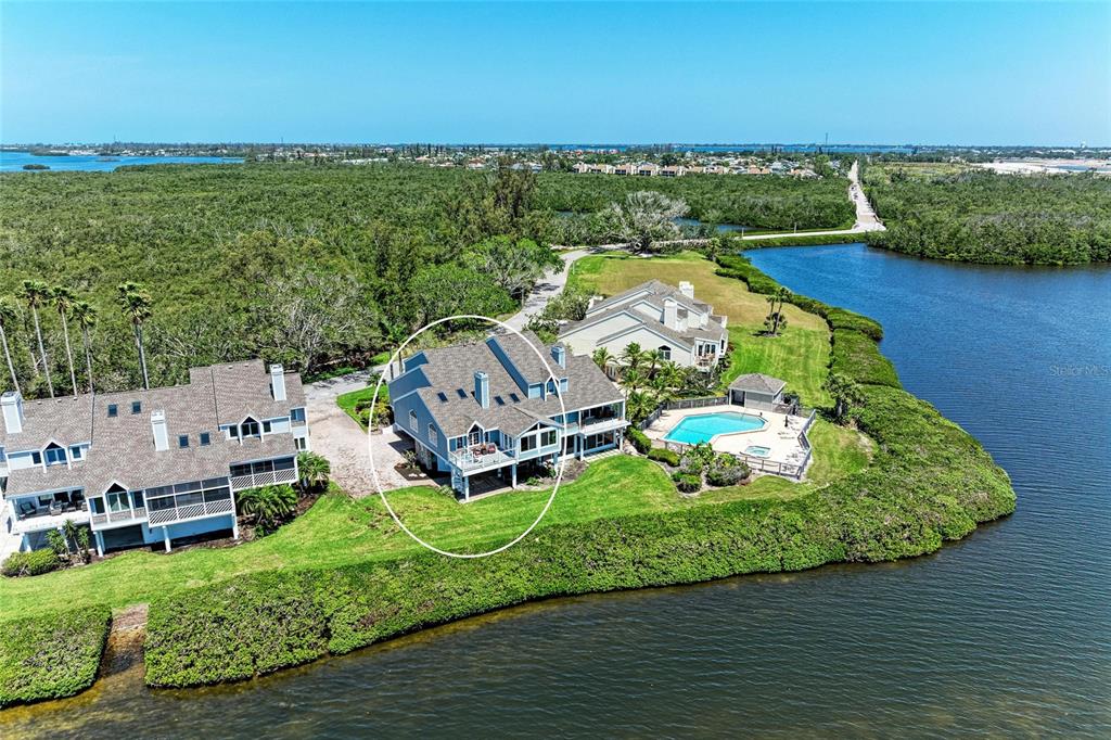 An aerial view shows a multi-story house with a deck overlooking a waterfront area — 12 TIDY ISLAND BOULEVARD, BRADENTON, FL