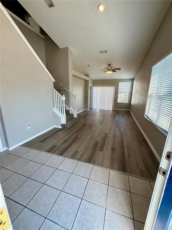 An open-concept living area features tile flooring in the foreground and wood-look flooring beyond — 9701 CARLSDALE DRIVE, RIVERVIEW, FL