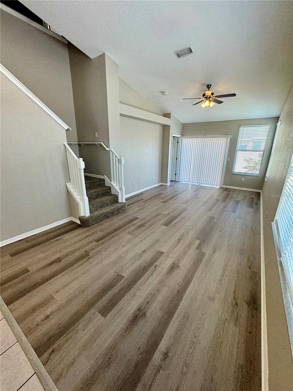 An empty living room features light wood-look flooring, a staircase, and a ceiling fan — 9701 CARLSDALE DRIVE, RIVERVIEW, FL