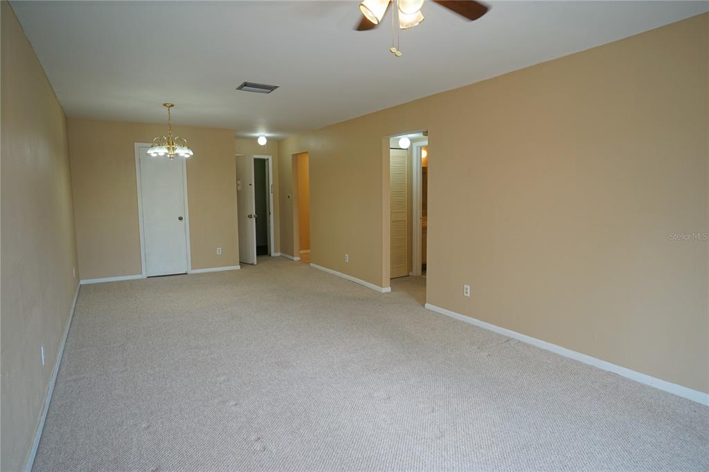 An empty room with beige walls, tan carpeting, a ceiling fan, and multiple doorways — 4610 W GRAY STREET UNIT 307, TAMPA, FL