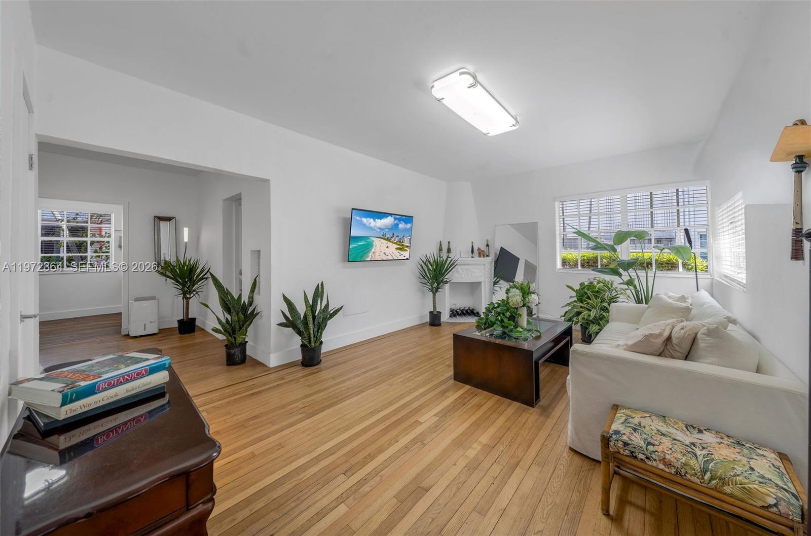 A living room features hardwood floors, white walls, a fireplace, and a white sofa — 1309 Euclid Ave # 6, Miami Beach FL 33139, MIAMI BEACH, FL