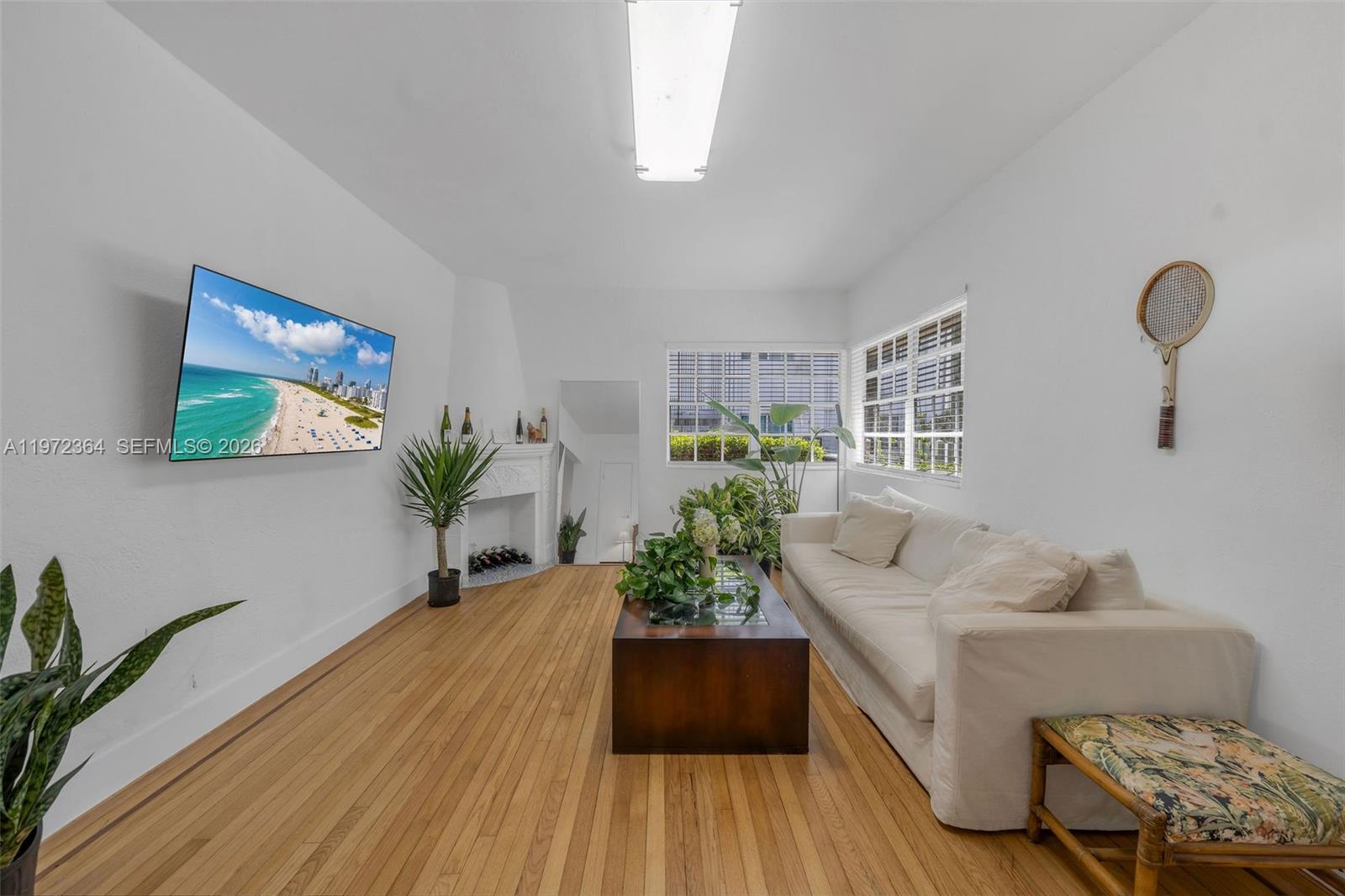 A living room features hardwood floors, a white sofa, a fireplace, and a wall-mounted television — 1309 Euclid Ave # 6, Miami Beach FL 33139, MIAMI BEACH, FL