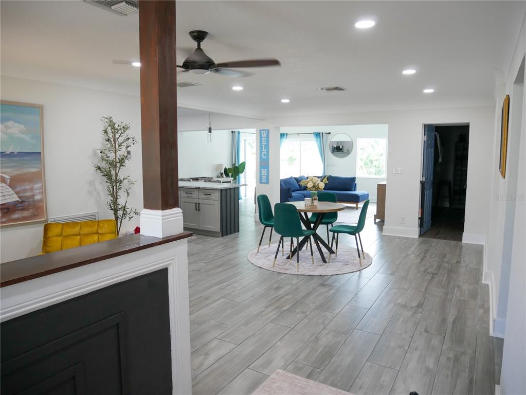 An open-concept living and dining area features gray wood-look tile flooring and recessed lighting — 8280 32ND AVENUE N, ST PETERSBURG, FL