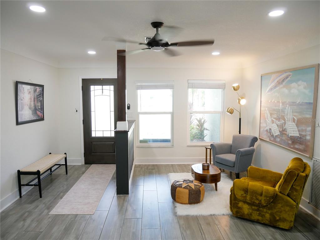 A living room features wood-look tile flooring, a ceiling fan, and two armchairs — 8280 32ND AVENUE N, ST PETERSBURG, FL