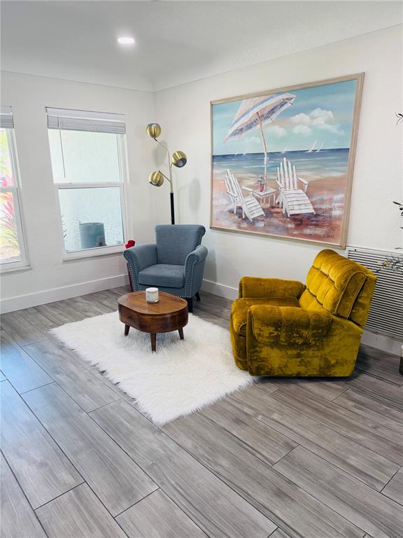 A room features a blue armchair, a yellow recliner, a coffee table, and beach-themed wall art — 8280 32ND AVENUE N, ST PETERSBURG, FL