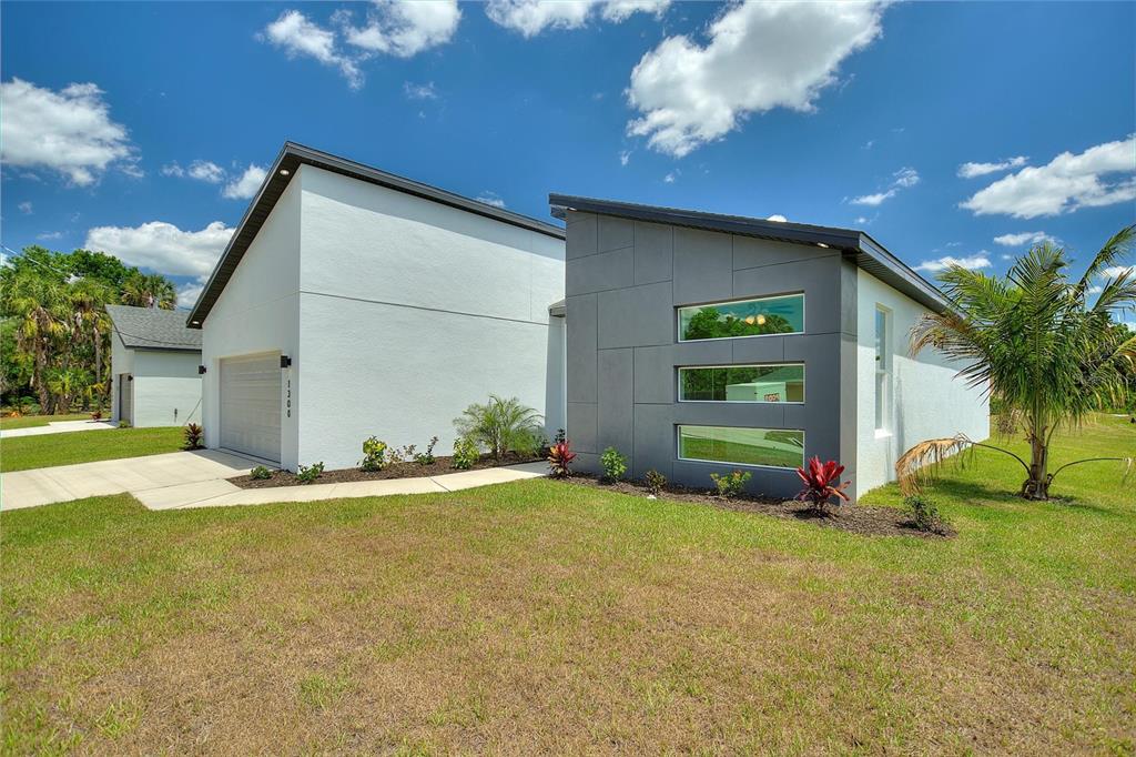A modern house exterior features white stucco walls, a gray paneled accent wall, and horizontal windows — 24399 SW KINGSWAY CIRCLE, ARCADIA, FL