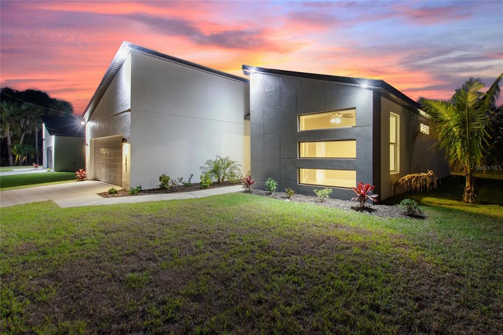 A modern house exterior features a gray paneled facade, horizontal windows, and a white garage — 24399 SW KINGSWAY CIRCLE, ARCADIA, FL