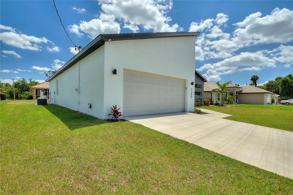 A white single-story house with a two-car garage and a concrete driveway under a sky — 24399 SW KINGSWAY CIRCLE, ARCADIA, FL