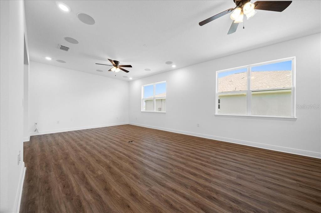 An empty room with white walls, wood-look flooring, two ceiling fans, and two windows — 8233 SW 93RD TERRACE, OCALA, FL