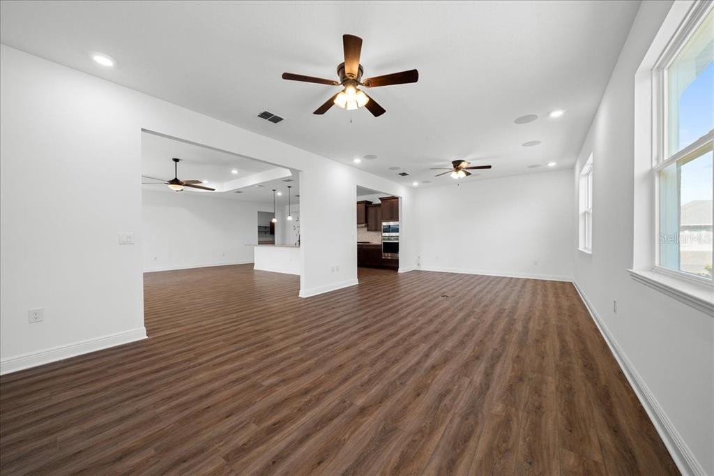 An open-concept living area features wood-look flooring, white walls, and multiple ceiling fans — 8233 SW 93RD TERRACE, OCALA, FL