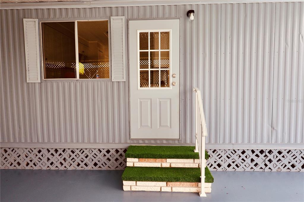 A white door and window are set into the corrugated metal siding of a home — 25163 MARION AVENUE UNIT 47, PUNTA GORDA, FL