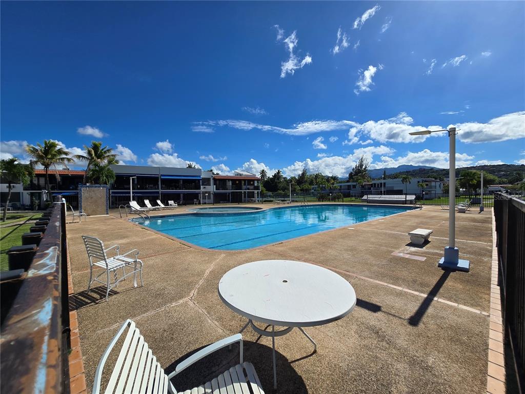 A swimming pool with lounge chairs and a table on a concrete deck outdoors — 351 LAS PICAUS, PLAYAS DEL YUNQUE UNIT 19, RIO GRANDE, PR