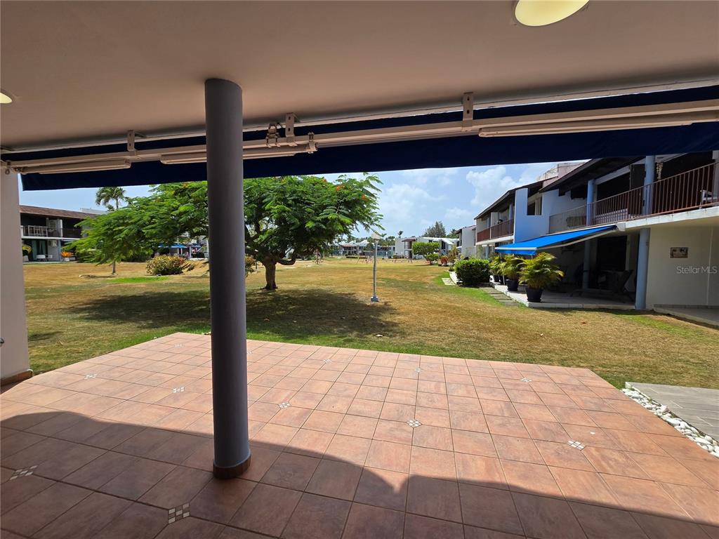 A tiled patio overlooks a grassy courtyard with trees and multi-story residential buildings — 351 LAS PICAUS, PLAYAS DEL YUNQUE UNIT 19, RIO GRANDE, PR