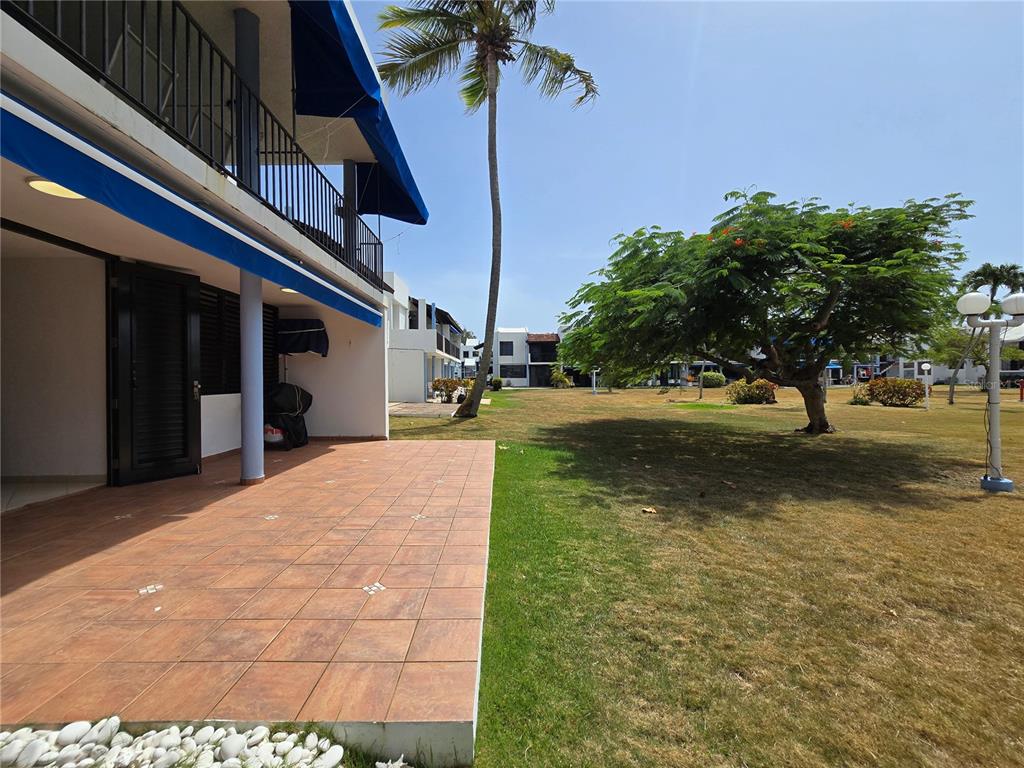 A tiled patio overlooks a grassy lawn with a large tree and a palm tree — 351 LAS PICAUS, PLAYAS DEL YUNQUE UNIT 19, RIO GRANDE, PR