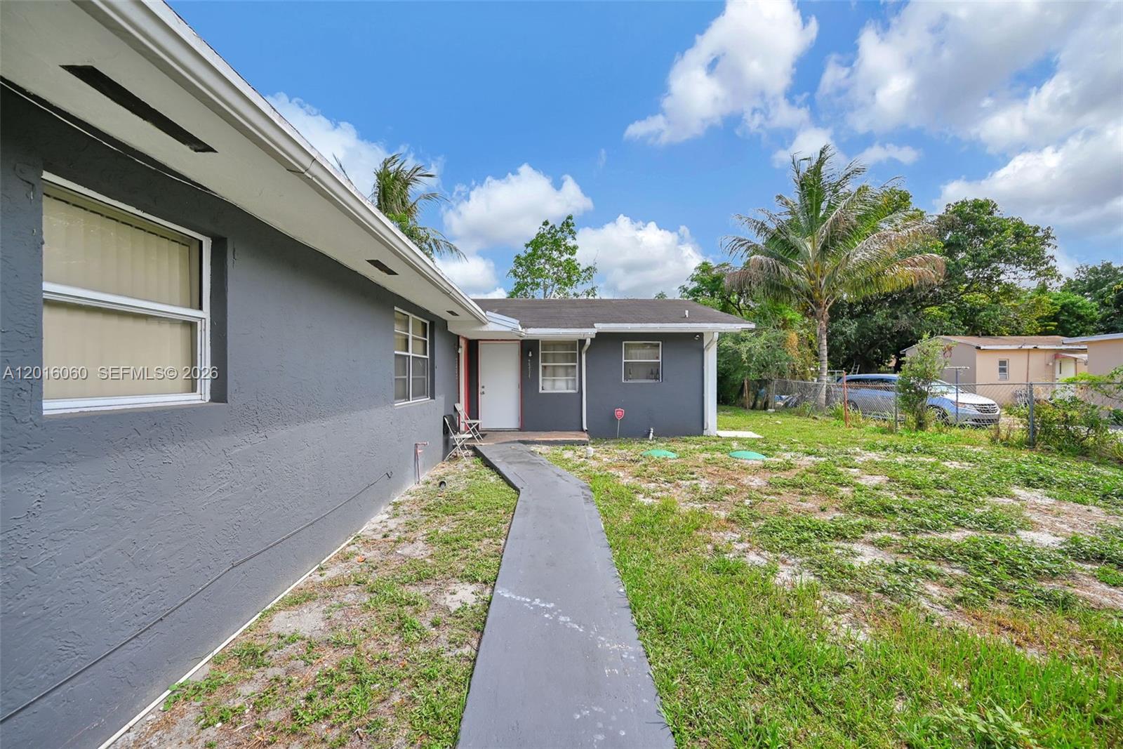 A gray house with a white front door features a paved walkway and grassy yard — 2352 NW 102nd St, Miami FL 33147, MIAMI, FL