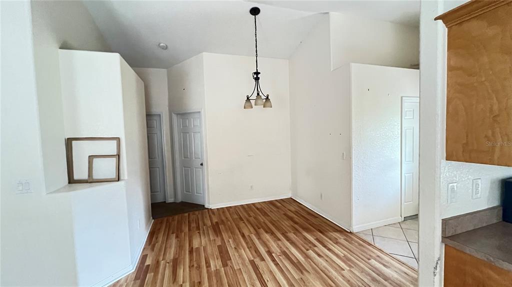 A dining area features wood-look flooring, a vaulted ceiling, and a hanging light fixture — 513 LEMON STREET, AUBURNDALE, FL