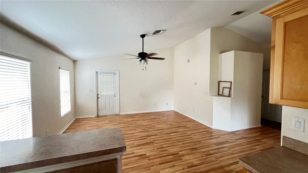 An open-concept room features light wood-look flooring, a ceiling fan, and a glass-paneled door — 513 LEMON STREET, AUBURNDALE, FL