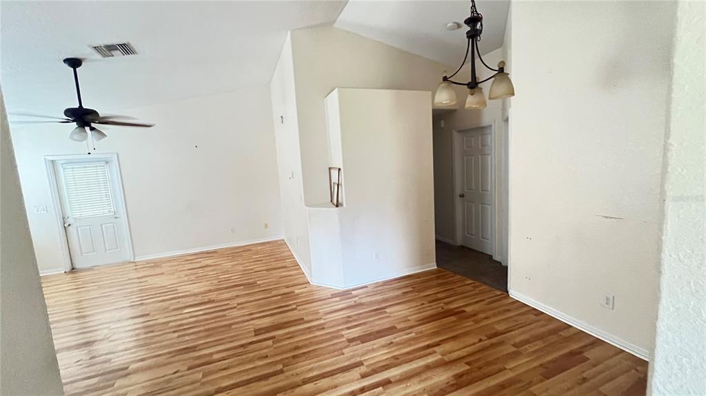 An interior view of a room with wood-look flooring, a ceiling fan, and a chandelier — 513 LEMON STREET, AUBURNDALE, FL