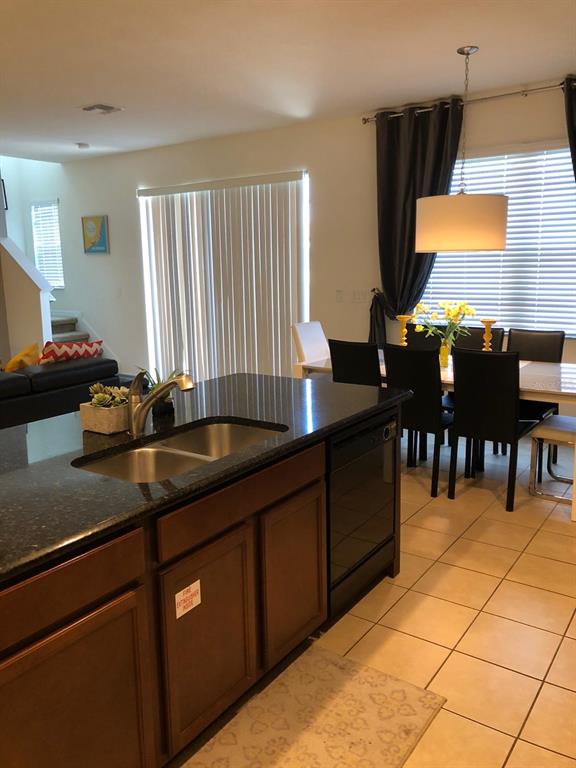 A kitchen island with a double sink overlooks a dining area and a living room — 921 LAS FUENTES DRIVE, KISSIMMEE, FL