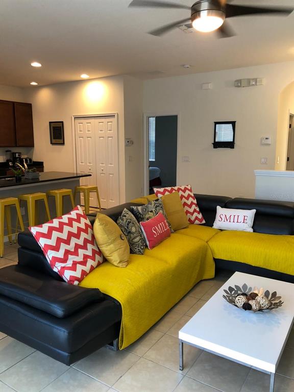 A living room features a black sectional sofa with yellow covers and a white coffee table — 921 LAS FUENTES DRIVE, KISSIMMEE, FL