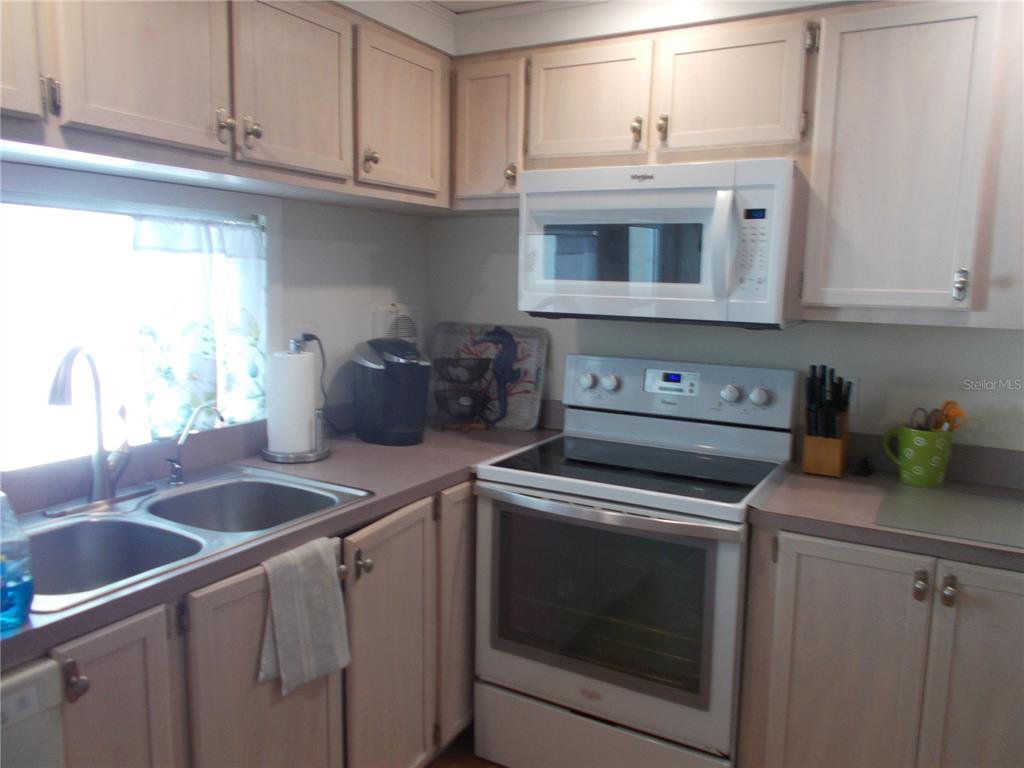 A kitchen features light wood cabinets, white appliances, a double sink, and a window — 5004 PALENA BOULEVARD, NORTH PORT, FL