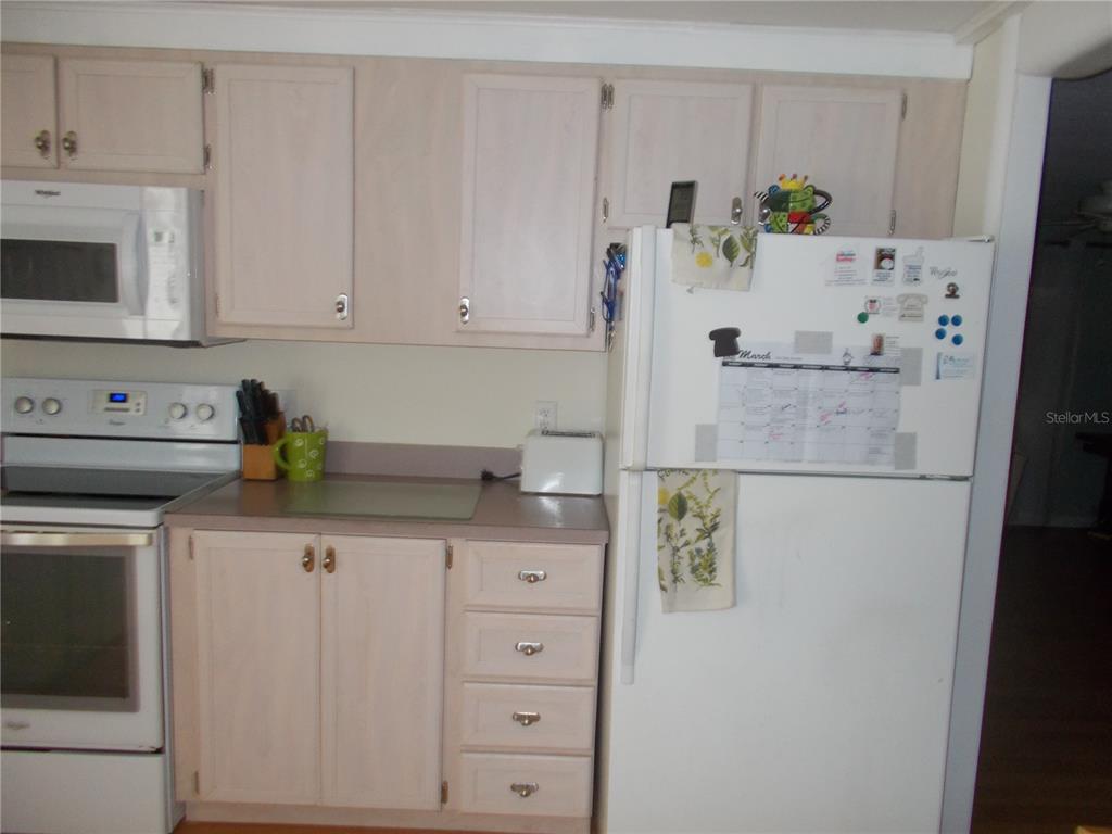 A kitchen features light wood cabinets, white appliances, and a white refrigerator with a calendar — 5004 PALENA BOULEVARD, NORTH PORT, FL