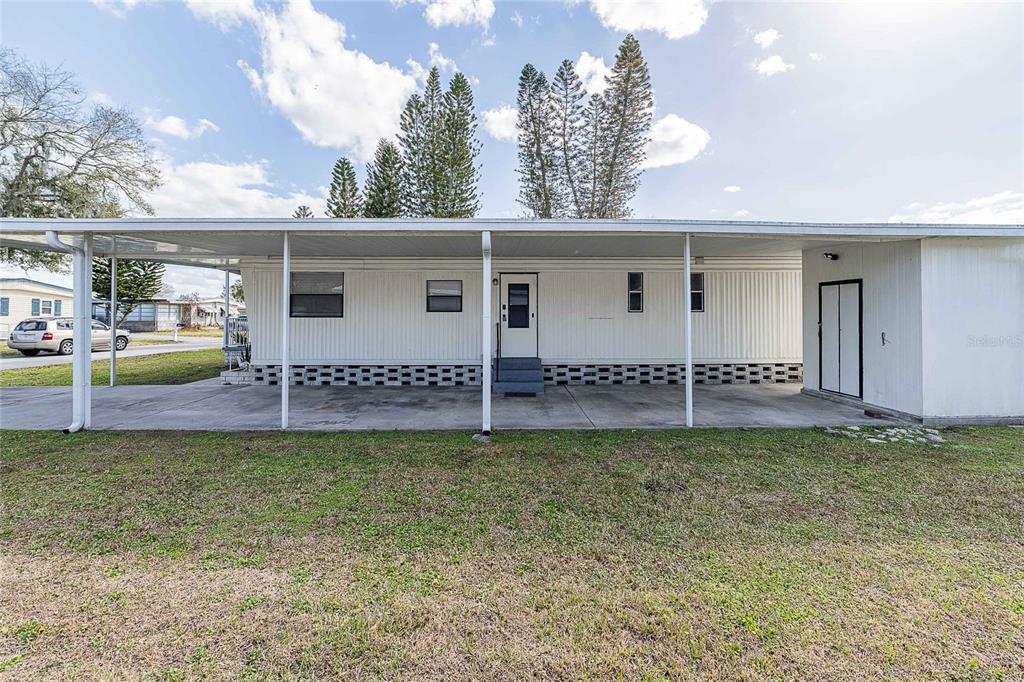 A mobile home with a large covered carport and a concrete driveway under a blue sky — 511 LAZY LAKE DRIVE W, LAKELAND, FL