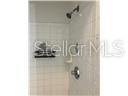 A tiled shower stall features a wall-mounted showerhead, a metal faucet, and a built-in shelf — 827 CAMARGO WAY UNIT 307, ALTAMONTE SPRINGS, FL