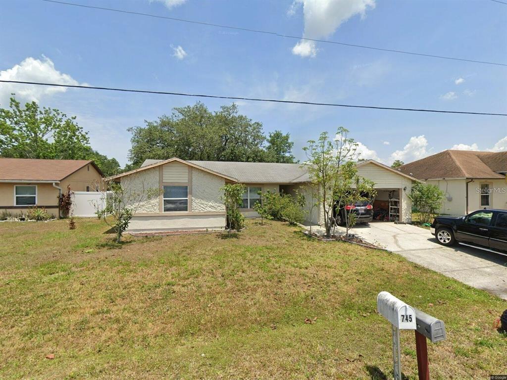 A single-story house with a beige stucco facade, a garage, and a front lawn — 746 MADERIA COURT, KISSIMMEE, FL