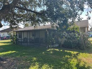 A side view of a house featuring a screened-in porch and a large shade tree — 746 MADERIA COURT, KISSIMMEE, FL