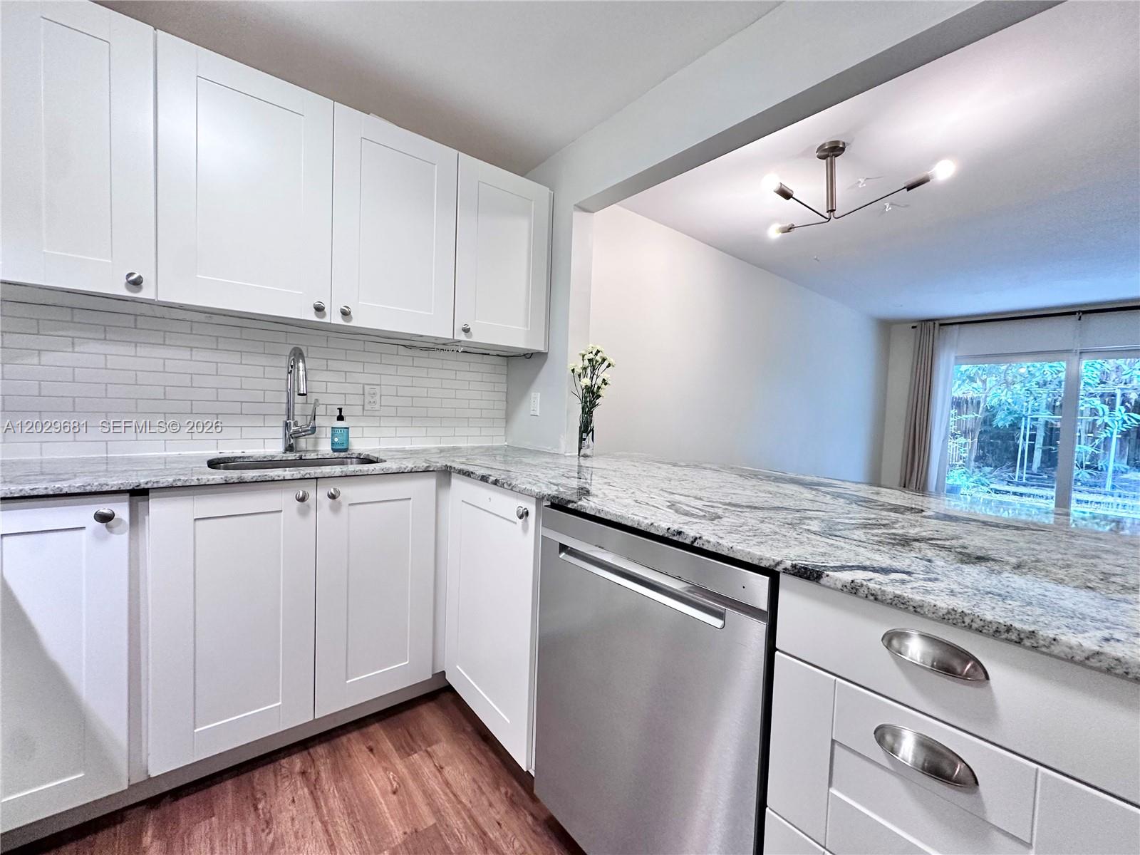 A kitchen features white shaker cabinets, granite countertops, stainless steel appliances, and wood-look flooring — 9974 SW 88th St # 1016, Miami FL 33176, MIAMI, FL