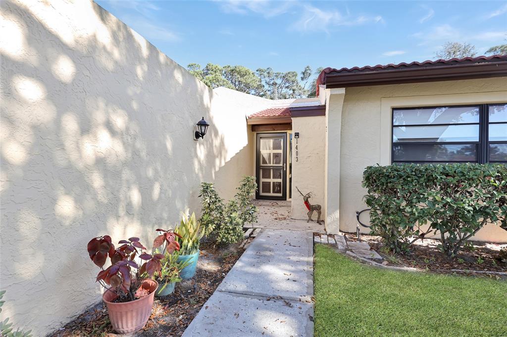 A concrete walkway leads to the front entrance of a house with stucco walls — 1403 56TH STREET W UNIT 1403, BRADENTON, FL